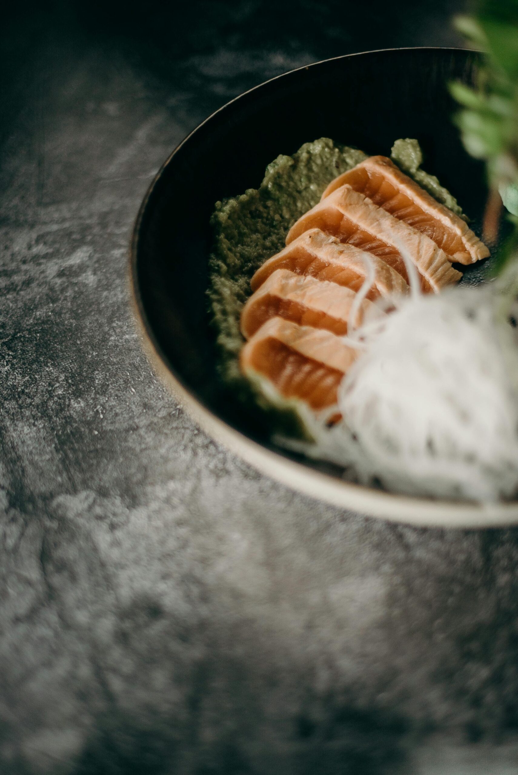 Fresh salmon sashimi served with garnish on a stylish dish, perfect for a premium dining experience.